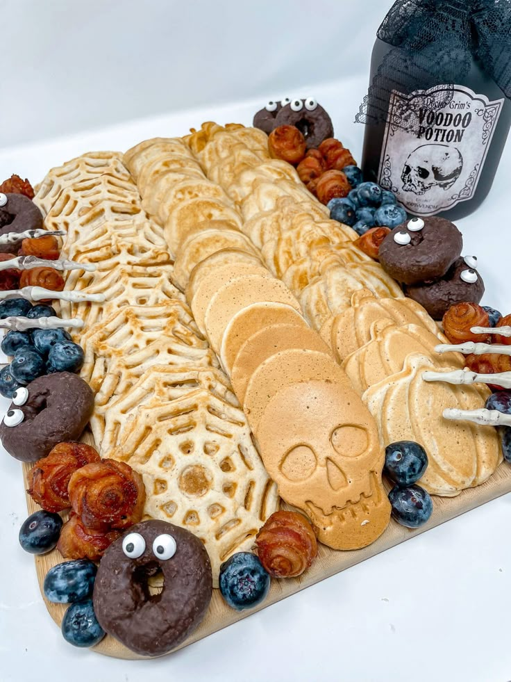 a platter filled with donuts, pretzels and blueberries next to a bottle of booze