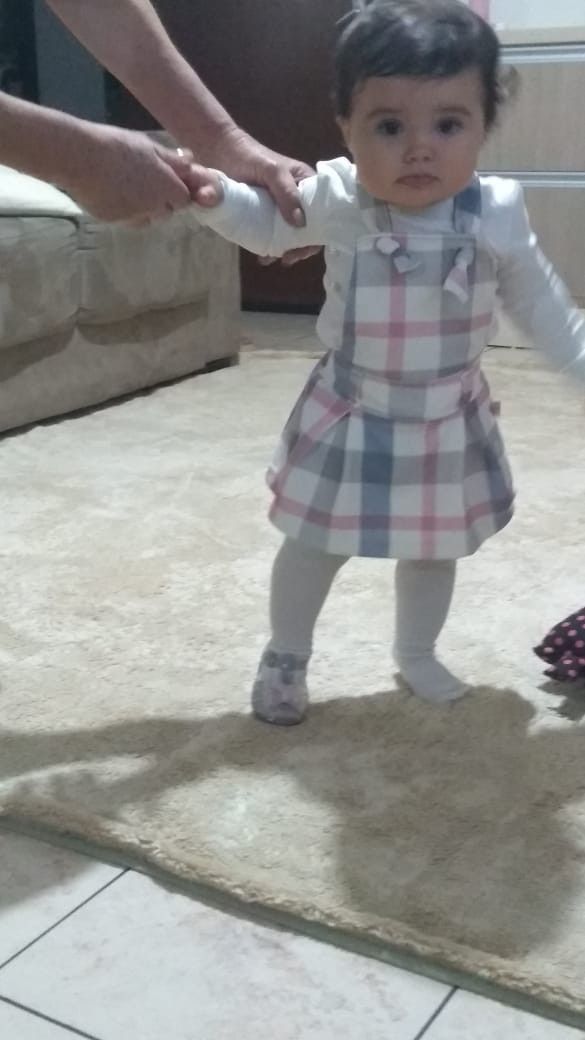 a baby girl is standing on the floor