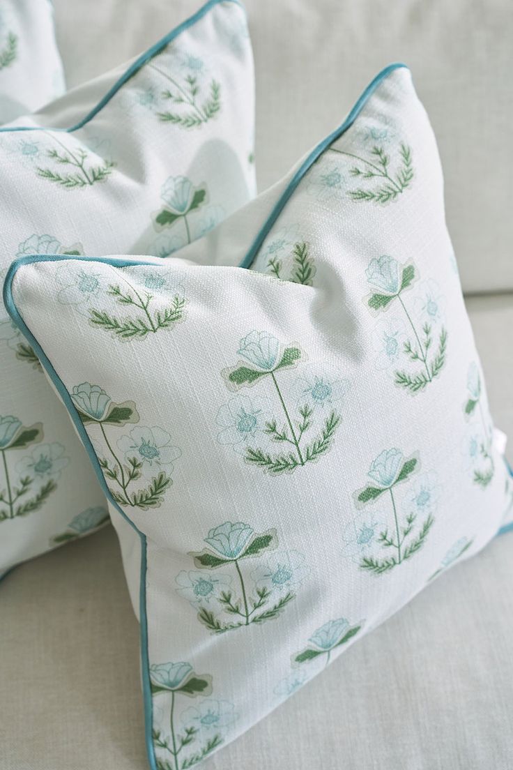 two pillows sitting on top of a couch next to each other with green plants printed on them