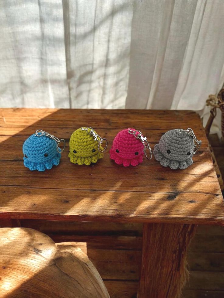 three crocheted elephants sitting on top of a wooden table