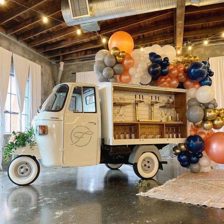 an ice cream truck is parked in front of balloons and streamers on the wall