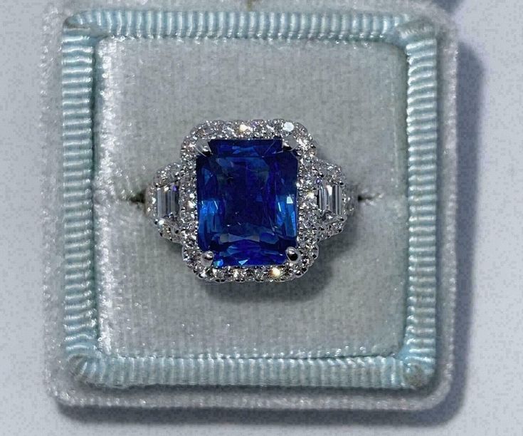 an engagement ring with a large blue stone surrounded by small white diamonds in a box