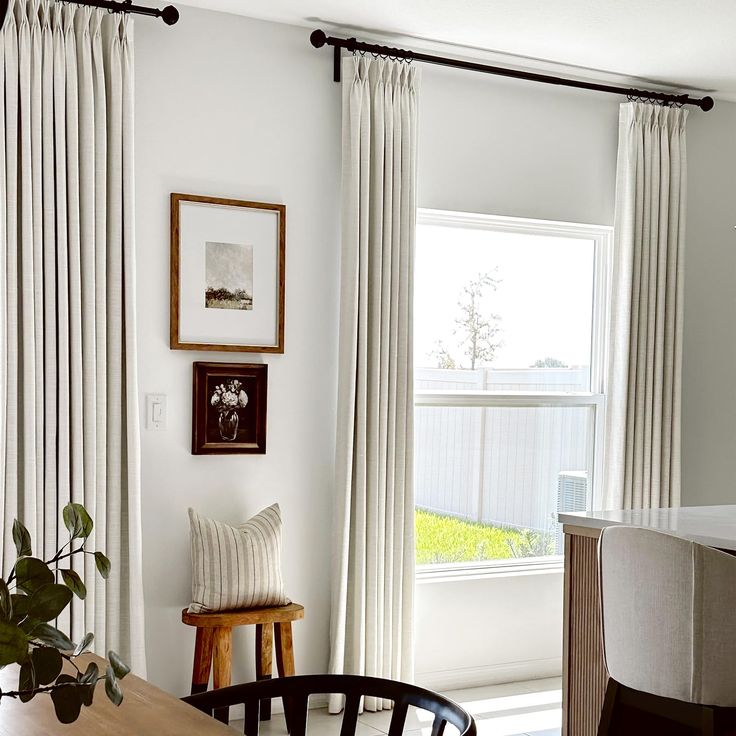 a living room with white curtains and a wooden table