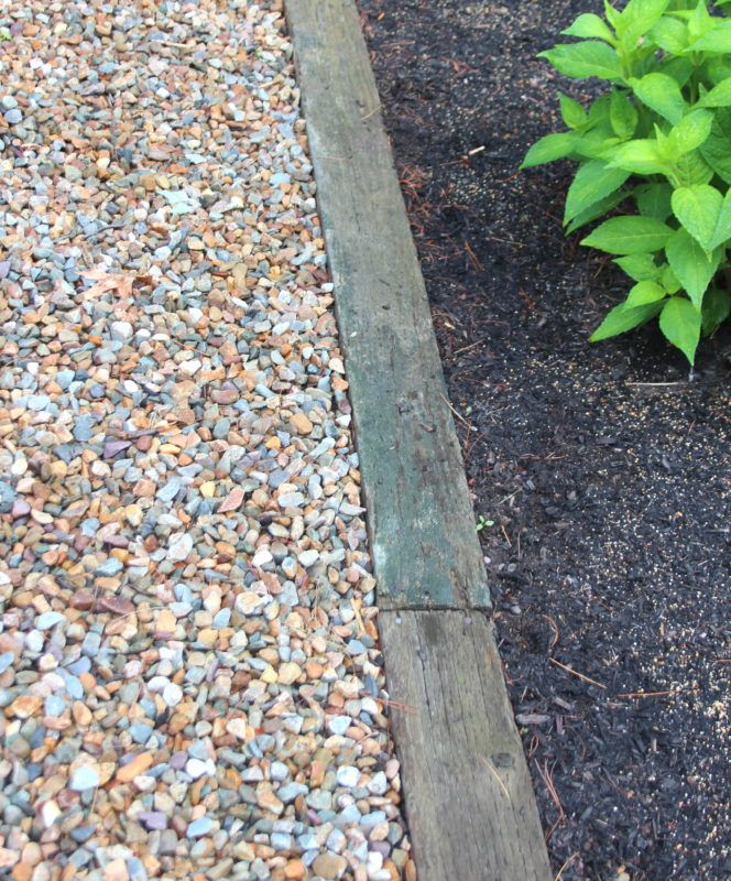 a garden with gravel and plants next to it