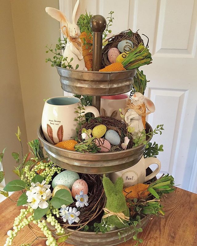 a three tiered tray with coffee cups and flowers on it, filled with eggs