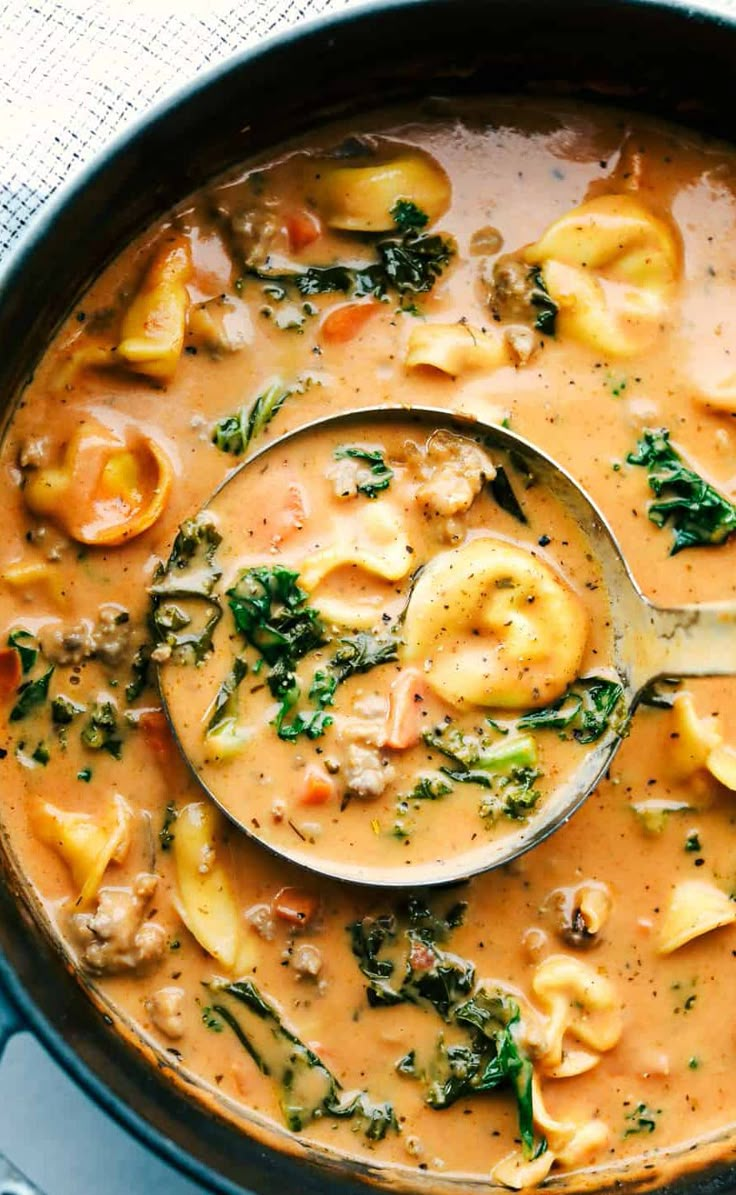 a ladle full of soup with dumplings and spinach on the side, ready to be eaten