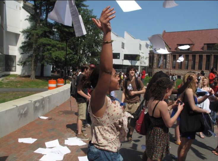 a group of people standing around each other with papers flying in the air