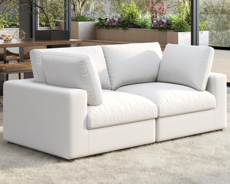 a white couch sitting on top of a carpeted floor next to a table and windows