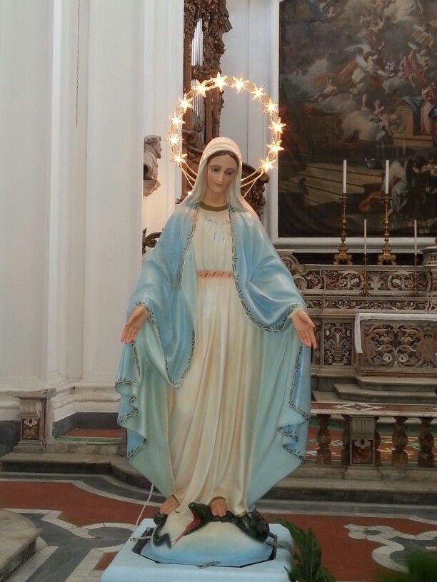 a statue of the virgin mary in front of a church alter with lights on it