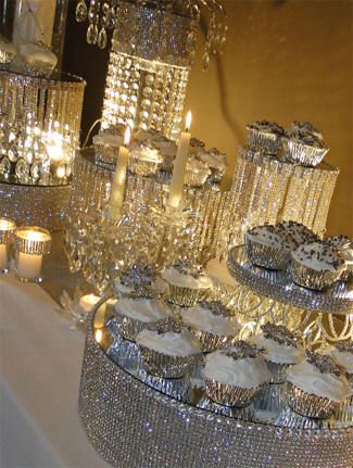 a table topped with lots of cakes and cupcakes covered in silver frosting