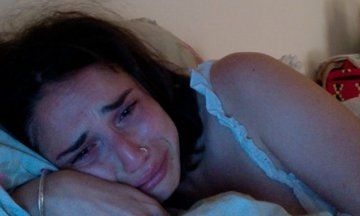 a woman is laying in bed with her head on the pillow and looking at the camera