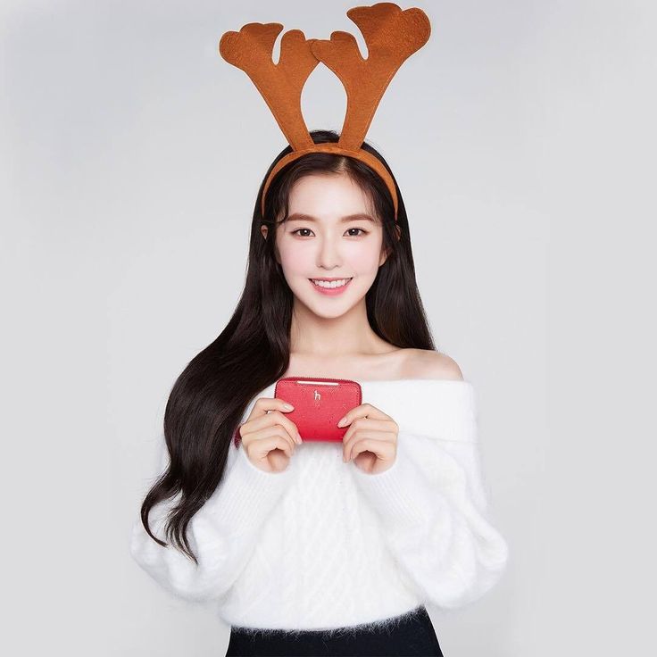 a young woman wearing reindeer antlers holding a red cell phone in front of her face