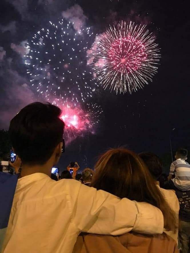 people are watching fireworks in the sky with their backs turned to look at them and one person is holding his arm out