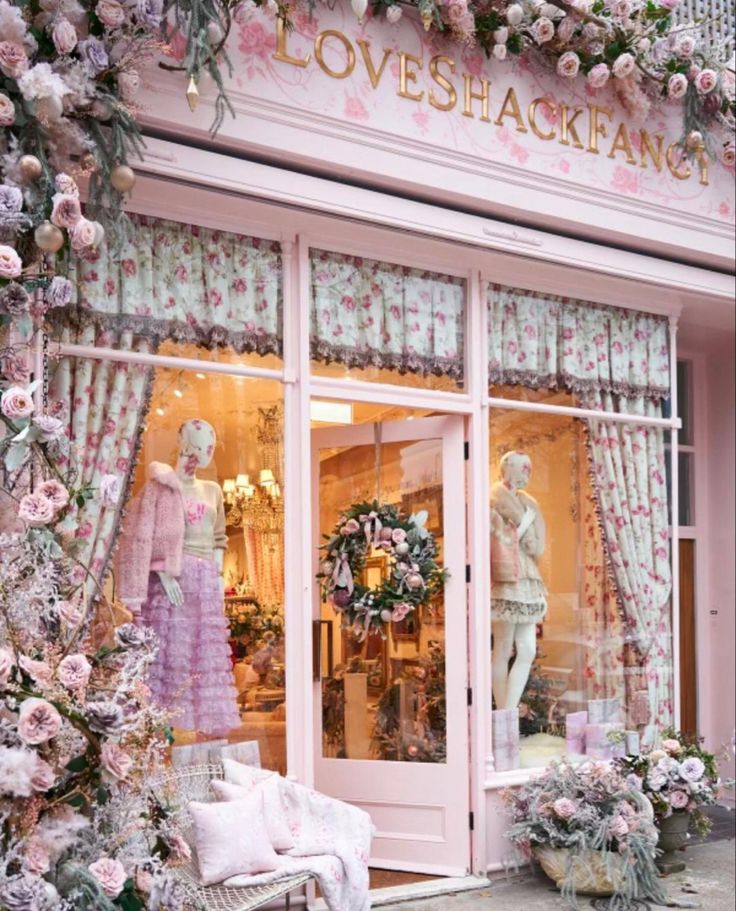 a store front with pink flowers and mannequins in the window