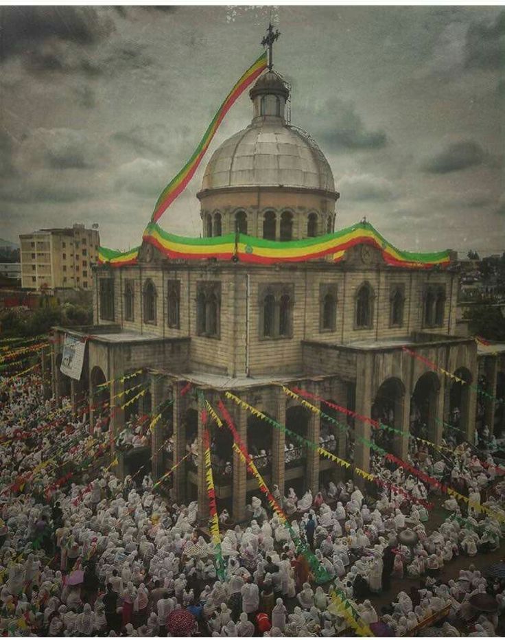 a large group of people standing in front of a building with a flag on it