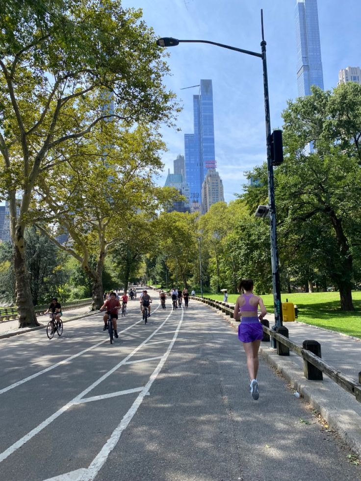 many people are riding bikes down the street in front of some tall buildings and trees