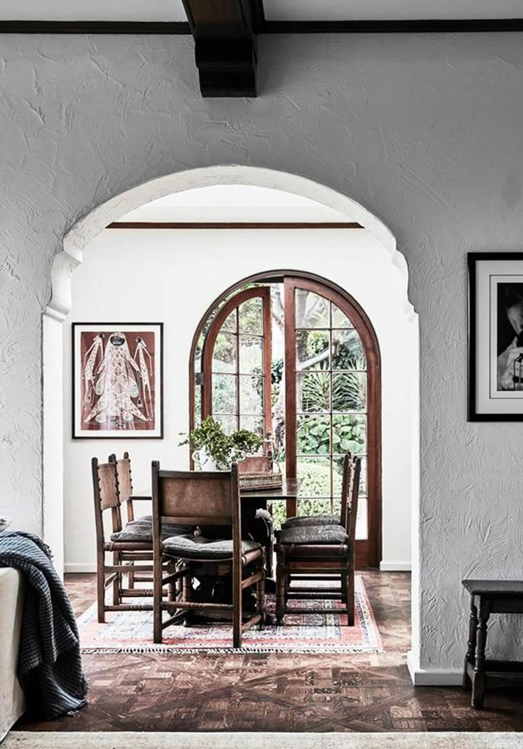 an arched doorway leads to a dining room with chairs and a table in the center