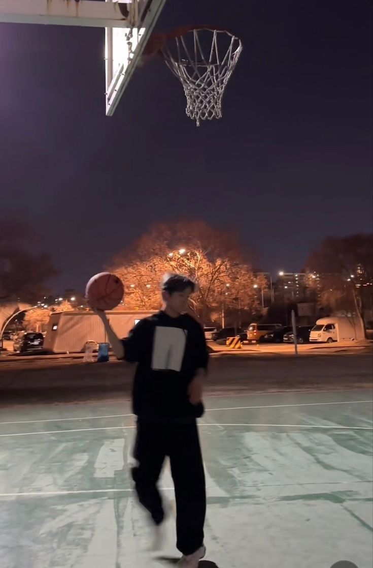 a man standing on top of a basketball court next to a hoop with a ball in it