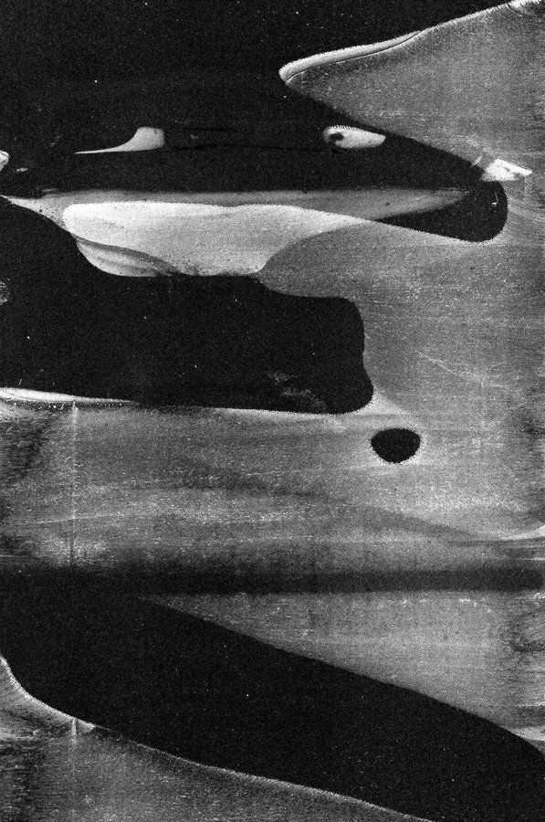 black and white photograph of water with two canoes in the background, taken from above