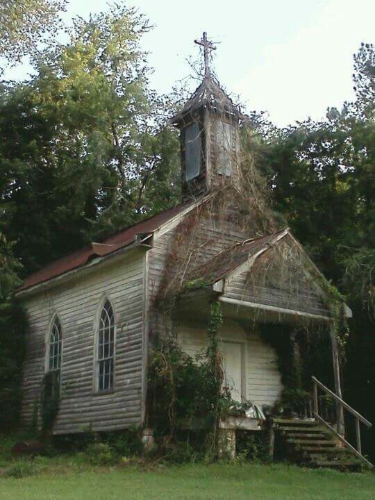 an old church with ivy growing on it's roof and stairs leading up to the steeple