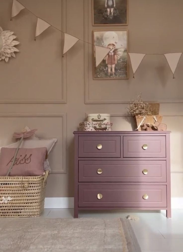 there is a dresser in the room with bunting on the wall and pictures above it