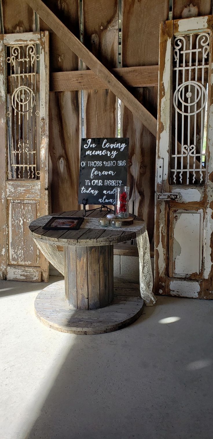 an old table with a sign on it in front of some wooden doors and stairs