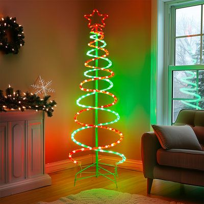 a christmas tree is lit up in the living room with green and red lights on it