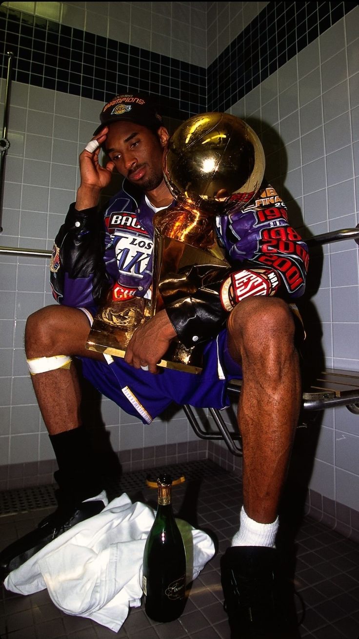 a man sitting on a toilet talking on a cell phone and holding a trophy in his hand