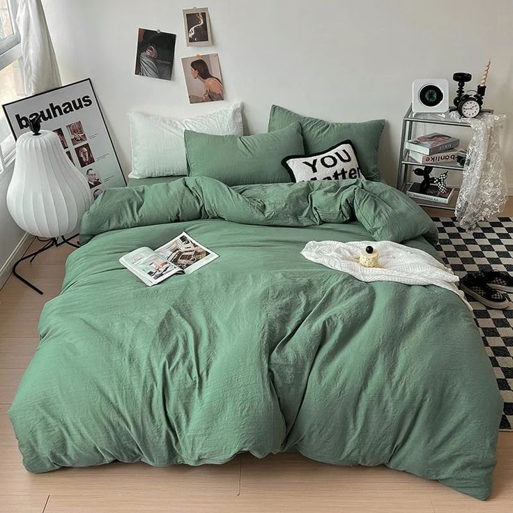 a bed with green comforter and pillows in a room next to a black and white checkered rug