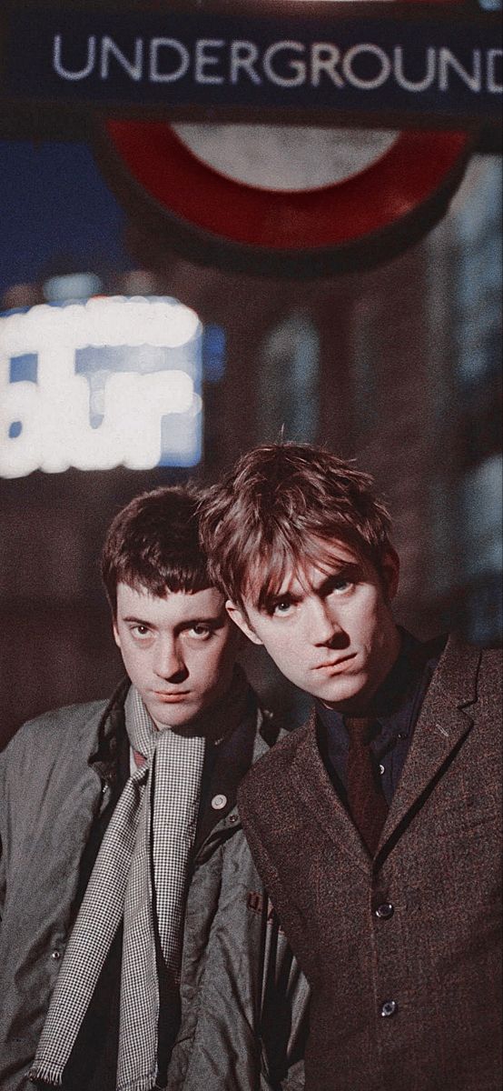 two young men standing next to each other in front of a sign that says underground