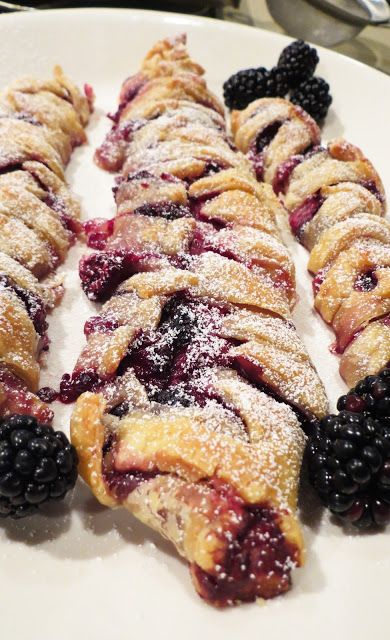 berry croissants are arranged on a plate with blackberries and powdered sugar