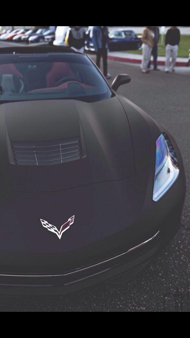 the front end of a black sports car parked in a parking lot next to other cars