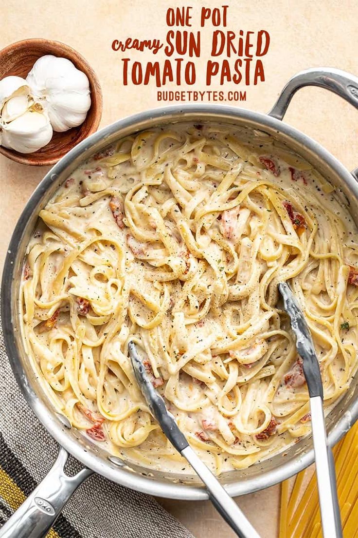 a pan filled with pasta and sauce next to garlic