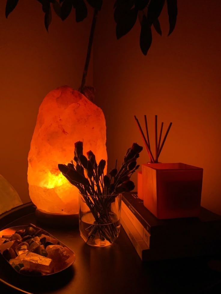 a table topped with a glass vase filled with flowers next to a lit candle and rocks