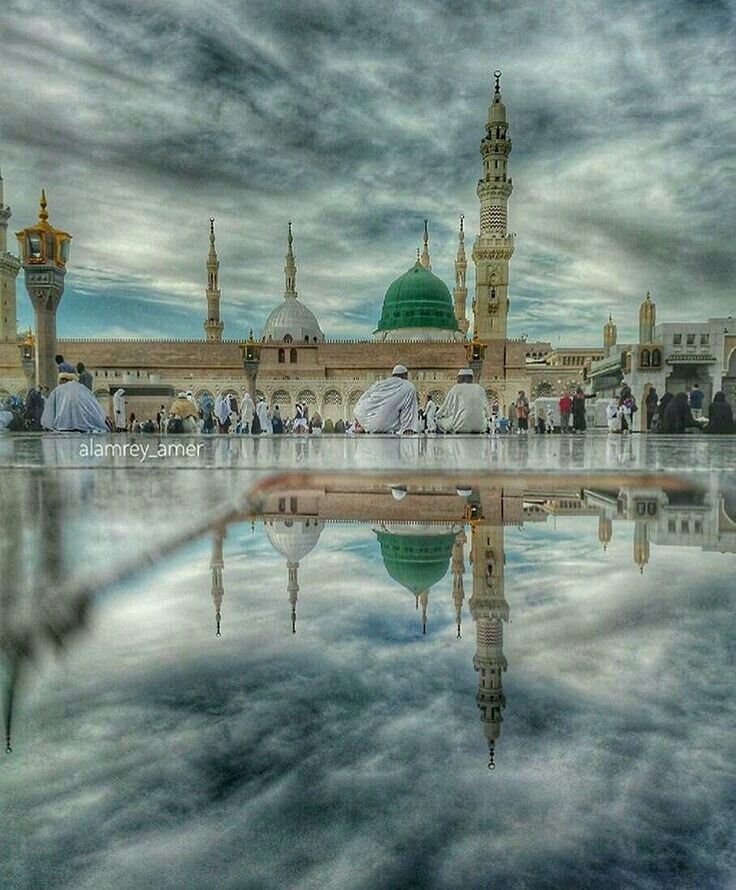 an image of a mosque in the middle of water with people walking around it and clouds above