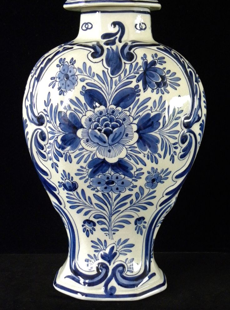 a large blue and white vase with flowers on it's sides, sitting in front of a black background