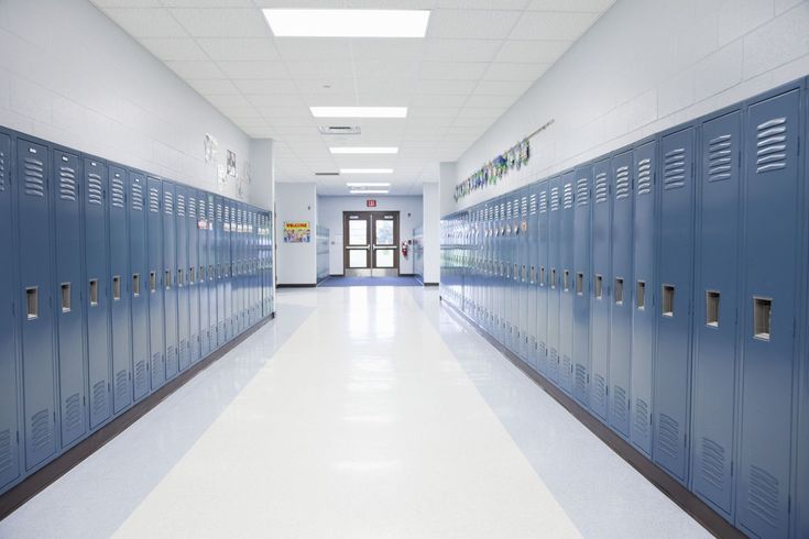 an empty hallway with blue lockers and doors