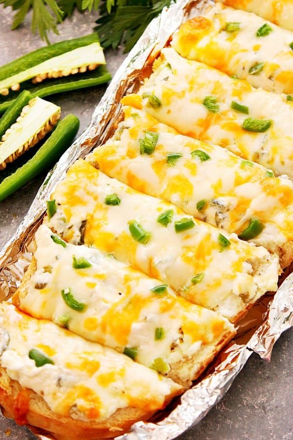 several pieces of food sitting on top of tin foil next to green beans and asparagus