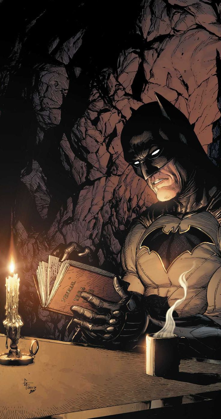 a batman sitting at a table reading a book with a candle in front of him