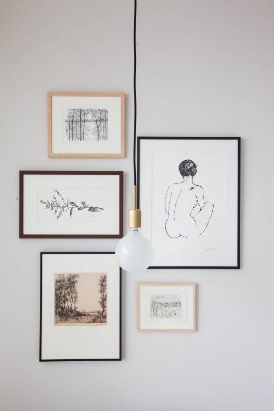 a white wall with pictures hanging on it and a light fixture in front of them