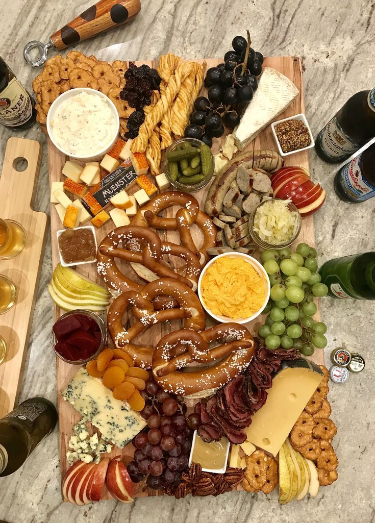 an assortment of cheeses, crackers, and other snacks on a wooden platter