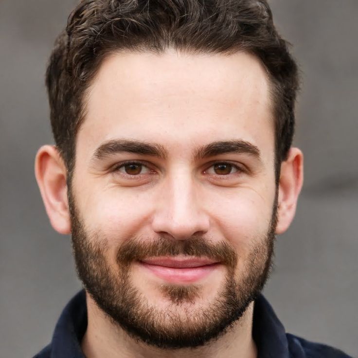 a close up of a person with a beard and shirt on smiling at the camera