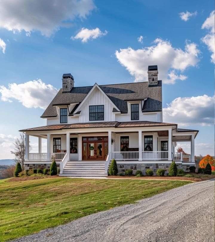 a large white house sitting on top of a lush green field next to a dirt road