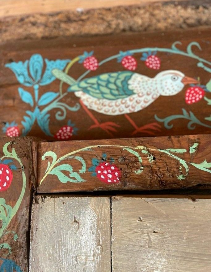 an old wooden bench with painted birds on it's sides and flowers around the edges