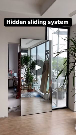 a large mirror sitting on top of a wooden floor next to a plant in a vase