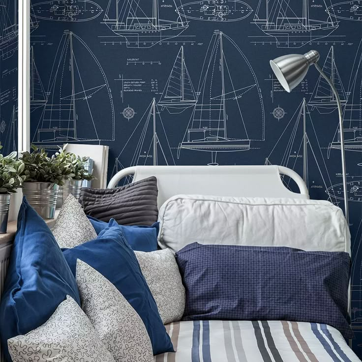 a blue and white bedroom with sailboats drawn on the wall next to bedding