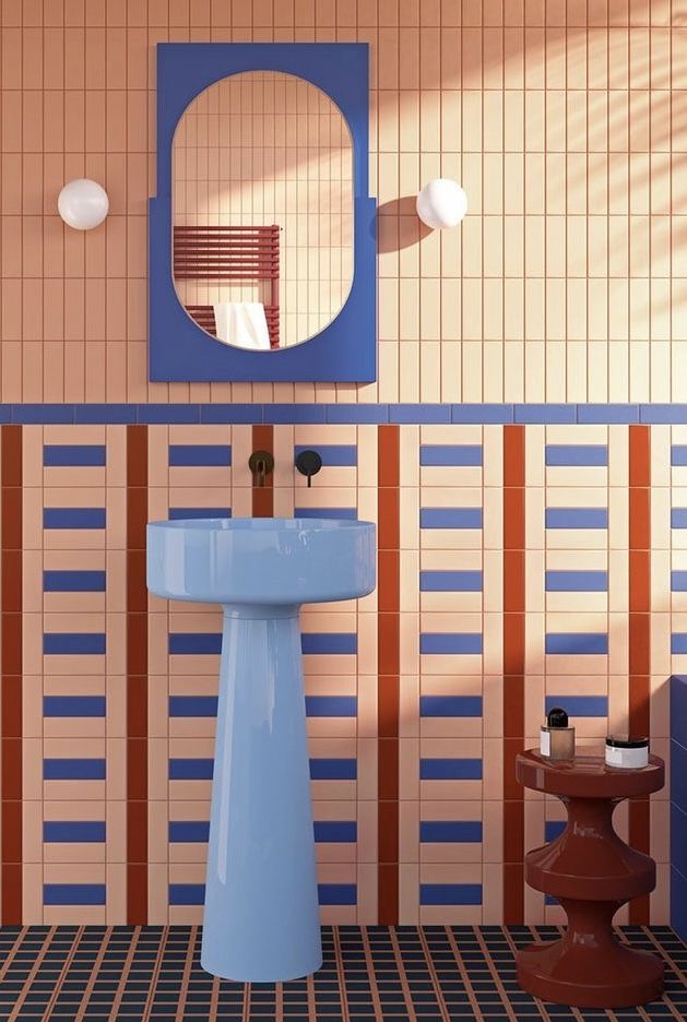 a blue pedestal sink sitting under a mirror next to a wall mounted faucet