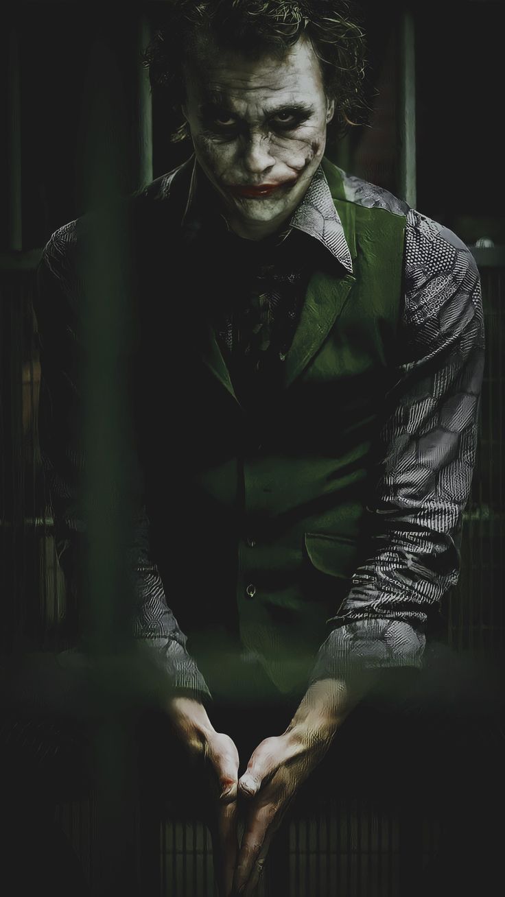 the joker is holding his hands together in front of a caged area with bars