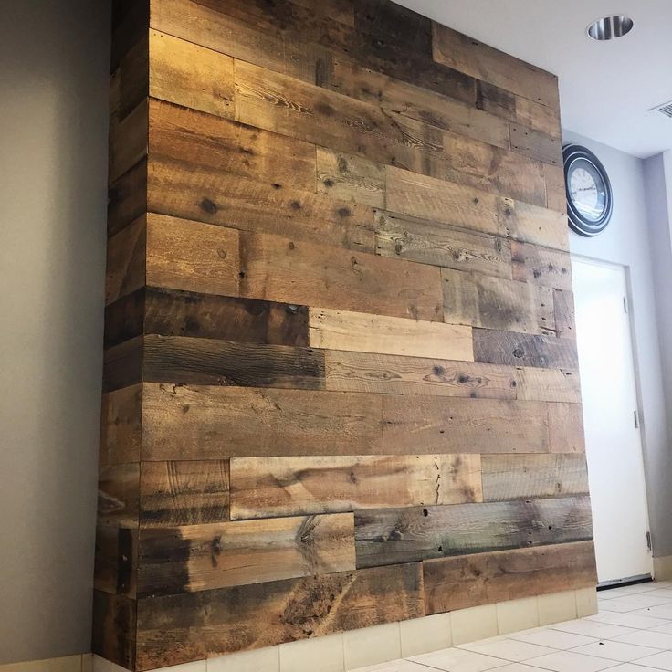 a wall made out of wooden planks with a clock in the background