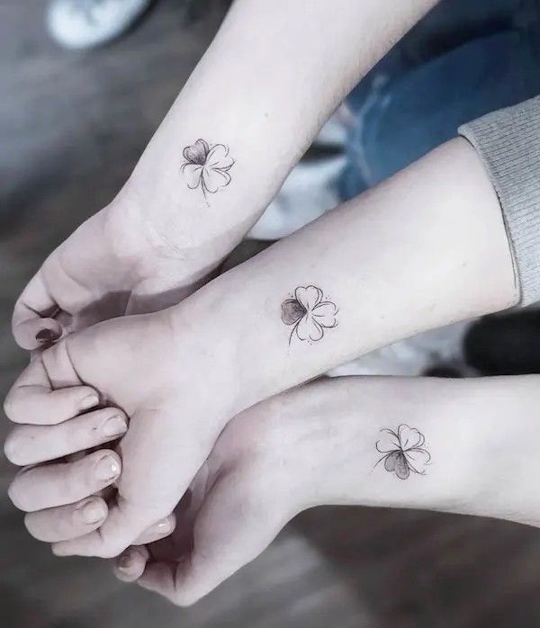 two people with matching tattoos on their arms holding hands and one has a clover tattoo